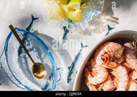 Sommer Meeresfrüchte Abendtisch verteilt, um Fisch Tacos, Garnelen, Guacamole, Limette, Tortilla, Salsa auf blauem und weißem Fischtischtuch in der Sonne Stockfoto