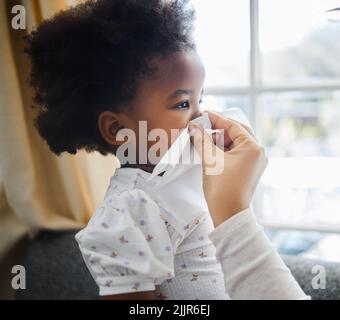 Mama gibt immer die beste Unterstützung. Ein kleines Mädchen bläst ihre Nase in ein Gewebe zu Hause. Stockfoto