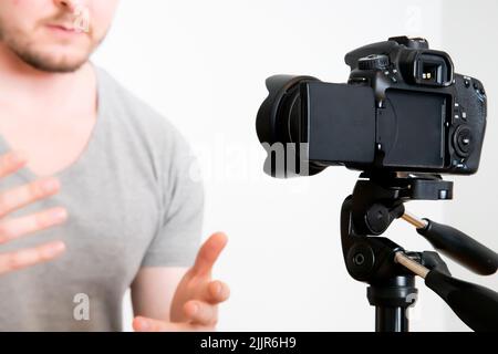 Ein Mann, der gegen eine isolierte Kamera auf weißem Hintergrund spricht Stockfoto