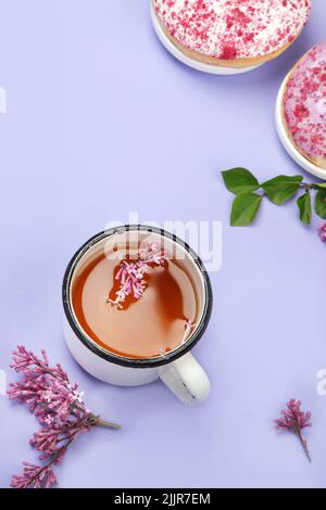 Fliederblumen mit einer Tasse Tee auf buntem Hintergrund. Stimmungsvolles Sommerkonzept. Draufsicht, flach liegend, Kopierbereich Stockfoto