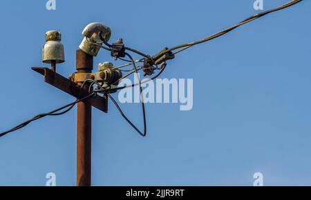 Ein alter Strommast, der Hochspannungsleitungen unterstützt, klarer Himmel Stockfoto