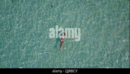 Eine Aufnahme über dem Kopf einer Frau in einem weißen Bikini im klaren Meerwasser der Insel Rasdhoo auf den Malediven Stockfoto