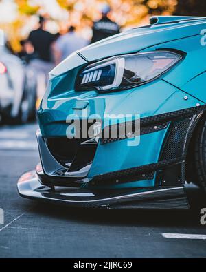 Seitenansicht eines blauen Sportwagens auf den Scheinwerfern und dem Felgenrad auf der Straße Stockfoto