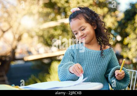 Jeden Tag intelligenter fühlen. Ein kleines Mädchen, das Hausaufgaben in ihrem Hof macht. Stockfoto