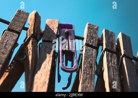 Eine Nahaufnahme von hölzernen Kleidernadeln, die an einem Seil an einem blauen Himmel hängen Stockfoto