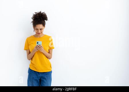 Schöne Frau hält ein Mobiltelefon, Online-Chat Einkaufen auf weißem Hintergrund lächelnd süß stehen Stockfoto