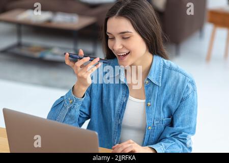Junge Freiberuflerin oder Büroangestellte, die im Heimbüro mit dem Mobiltelefon spricht Stockfoto