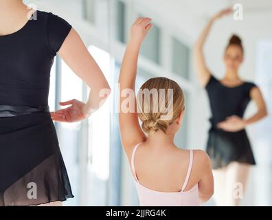 Ballett etwas reines in dieser verrückten Welt. Ein kleines Mädchen übt Ballett mit ihrer Lehrerin in einem Tanzstudio. Stockfoto