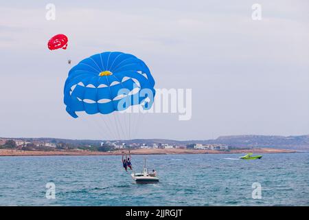 Ayia Napa, Zypern - 16. Juni 2018: Parasailing Motorboot mit Touristen in Agia Napa Bucht Stockfoto