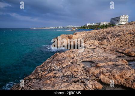 Küstensommerlandschaft der Urlaubsstadt Ayia Napa. Die felsige Küste der Insel Zypern steht unter einem dramatischen stürmischen Himmel Stockfoto