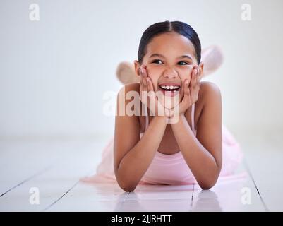 Ballerinas sind die Besten. Ein kleines Mädchen, das in einem Ballettstudio auf dem Boden liegt. Stockfoto