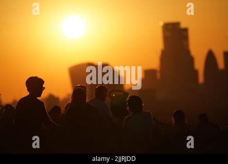 Fileboto vom 17/07/21 von Menschen im Greenwich Park, die den Sonnenuntergang über London beobachten, da die „unauffälligen“ Temperaturen des vergangenen Jahres erst vor wenigen Jahrzehnten nahezu rekordverdächtig gewesen wären, was zeigt, wie sich das britische Klima verändert, sagte das Met Office. Stockfoto