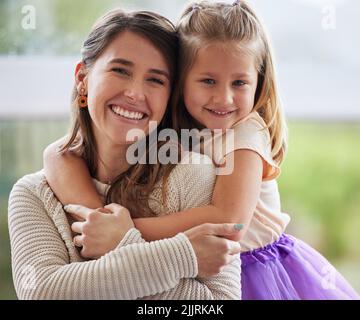 Sie gibt mir so viel Freude. Ein kleines Mädchen umarmt ihre Mutter zu Hause. Stockfoto