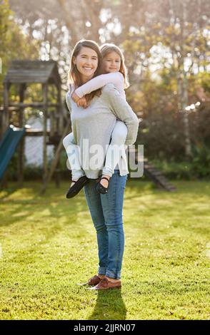 Wohin, meine Liebe. Ganzkörperportrait einer attraktiven jungen Frau und ihrer Tochter, die zu Hause im Garten posiert. Stockfoto