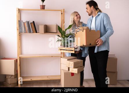 Paar zieht in eine neue Wohnung. Junges Paar mit Kisten, die in eine neue Wohnung ziehen. Viele Packkartons um sie herum. Neues Zuhause und Umzug Stockfoto