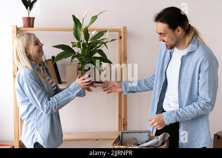 Glückliches junges Paar, das in ihrer neuen Wohnung umzieht, bewegter Tag. Auspacken und Zusammenarbeiten. Neues Zuhause für eine junge Familie. Was für eine Freude Stockfoto