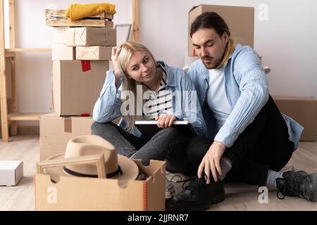 Paar zieht im Haus, glückliches Paar entspannt, während in der Nähe von Kartons in neue Heimat sitzen, Menschen, Umzug und Immobilien Stockfoto