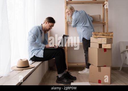 Junge verheiratete Paar ziehen in neues Zuhause, entspannen Sie sich auf dem Boden nach dem Auspacken Dinge Verwenden Sie Laptop für die Suche nach Hause Dekoration Ideen im Internet, Moving Day Stockfoto
