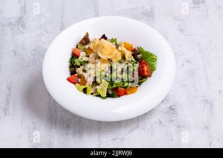 Eine Nahaufnahme von leckerem Caesar-Salat, serviert in einem weißen Gericht auf weißer Marmoroberfläche Stockfoto