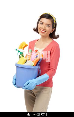 Fröhliche asiatische Frau mit charmanten Lächeln abgelenkt vom Frühling sauber, um für die Fotografie zu posieren, hält sie Eimer mit Reinigungsutensilien in den Händen Stockfoto