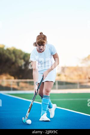 Arbeiten an meinen Dribbling-Fähigkeiten. Ganzkörperaufnahme einer attraktiven jungen Frau, die alleine Hockey spielt. Stockfoto