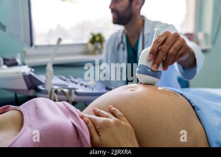 Eine Schwangerin beim Gynäkologen, die ihr Baby mit einem Ultraschallgerät untersuchen ließ. Stockfoto