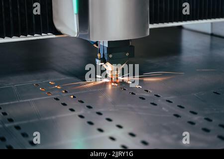 Nahaufnahme einer Laserschneidemaschine mit Funken. CNC-Plasmaschneider schneiden Metallblech. Gasschneideverfahren im Werk Stockfoto