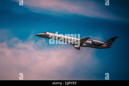 Ein Passagierflugzeug, das gegen den wolkenblauen Himmel fliegt Stockfoto