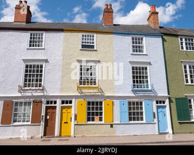 An einem sonnigen Tag sind drei Stuckziegelhäuser mit Schimpansen und braunen, gelben und blauen Türen entlang einer Straße in Oxford angebracht. Stockfoto