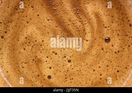 Eine Makroaufnahme von Kaffee-Milchschaum. Hintergrundtextur von Espresso, Kaffeecreme. Stockfoto