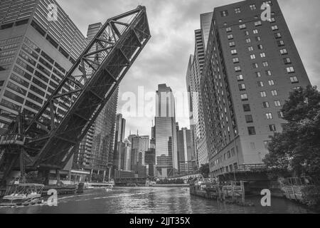 Eine Graustufenaufnahme des Chicago River mit einer offenen Brücke Stockfoto