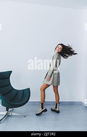 Schöne Brünette Frau in einem herbstlichen Trenchcoat und Lederstiefel posiert im Studio. Damenmode Stockfoto