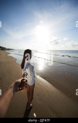 Schöne Frau am Strand hält Hand von ihrem Freund Stockfoto