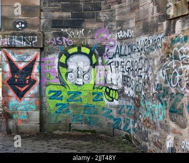 Bunte Graffiti auf einer Steinmauer entlang des Kanalweges in Edinburgh Stockfoto