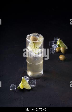 Cocktail mit Gin, Petersilie, Zitrone, Olive und Crushed Ice auf dunklem Grund. Cocktailkarte Getränkefotografie, Kopierfläche. Selektiver Fokus. Stockfoto