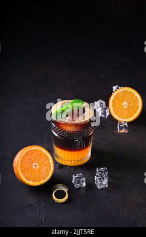 Michelada Mexikanisches Getränk mit Bier. Erfrischendes Sommergetränk mit dunklem Bier, Limettensaft, Orangen und Eis in einem Glas-Kelch Stockfoto