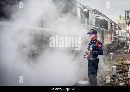 Bangkok, Thailand. 28.. Juli 2022. Ein Offizier der SRT (State Railway of Thailand) steht in einer großen Dampfwolke, während der Zug vorbeifährt. Königliche Fans und Zugenthusiasten treffen sich auf der nordwärts gelegenen Plattform am Bahnhof Hua Lamphong in Bangkok zu einer Dampfeisenbahnfahrt nach Ayutthaya (die ehemalige Hauptstadt von Siam) anlässlich des 70.. Geburtstages von König Vajiralongkorn am 28. Juli 2022. Die Dampflokomotiven aus der Zeit des Zweiten Weltkriegs wurden für eine begrenzte, denkmalliche Verwendung für den Tourismus restauriert. Kredit: SOPA Images Limited/Alamy Live Nachrichten Stockfoto