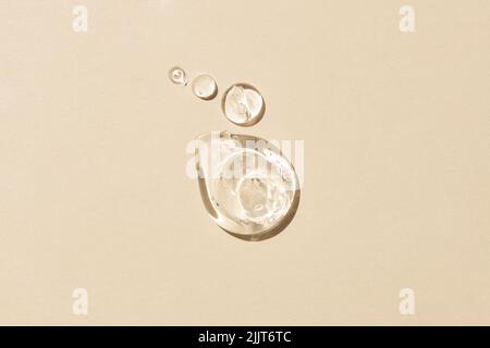 Glyzerin-Gel-Textur. Transparenter Serumtropfen auf beigem Hintergrund. Flüssige Gel Feuchtigkeitscreme mit Blasen Makro. Stockfoto