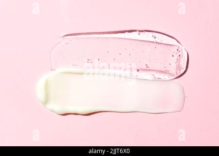 Weiße Creme und transparente Geltextur auf einem rosa Hintergrund. Hautpflegeprodukte verschmieren. Stockfoto
