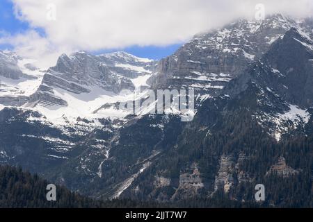 Hervorragend sichtbare Bergfelsen von alpinen Gipfeln, bedeckt mit dunkelgrünem Wald und Schnee, Ville d'Anaunia, Trentino, Italien Stockfoto