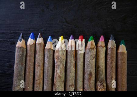 Eine Reihe von Farbstiften aus Holz, isoliert auf dunklem Hintergrund Stockfoto