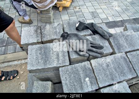 Ein großer Stapel von gestapelten Betonpflasterplatten und Arbeitshandschuhen auf ihnen Stockfoto