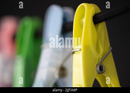 Den Helder, Niederlande. Juli 2022. Farbige Plastikkleidernadeln auf einer Wäscheleine. Hochwertige Fotos. Nahaufnahme. Isoliert auf Schwarz. Selektiver Fokus. Stockfoto