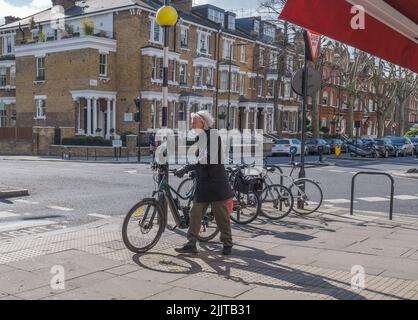 Ein Mann geht mit dem Fahrrad auf dem Bürgersteig an der Ecke Randolph Avenue und Elgin Avenue, Maida Vale, Westminster, London. Stockfoto