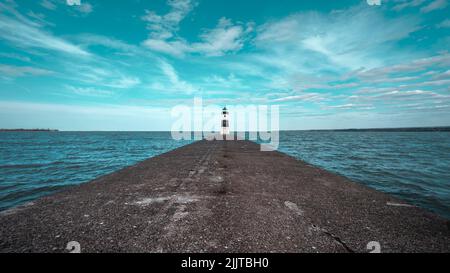 Ein Leuchtturm am Ende eines langen Piers über dem Erie-See unter einem wolkigen blauen Himmel Stockfoto