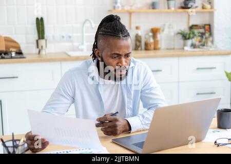 Porträt eines fokussierten freiberuflichen Geschäftsmannes, der die jährliche Umsatzübersicht analysiert und von zu Hause aus arbeitet Stockfoto