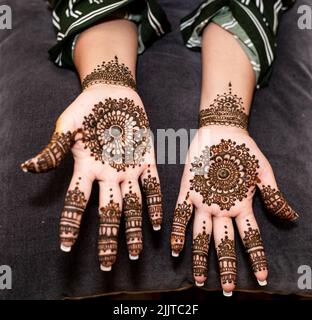 Die Hände eines mit Henna bemalten Weibchens Stockfoto