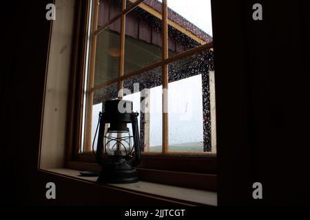 Eine Nahaufnahme einer alten schwarzen Öltischlampe auf einer hölzernen Fensterbank Stockfoto