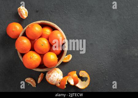 Holzschale aus Mandarine auf dunklem Hintergrund mit Kopierraum Stockfoto
