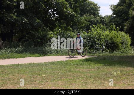 Mann in den Siebzigern mit dem Fahrrad durch den Nonsuch Park Surrey England Stockfoto